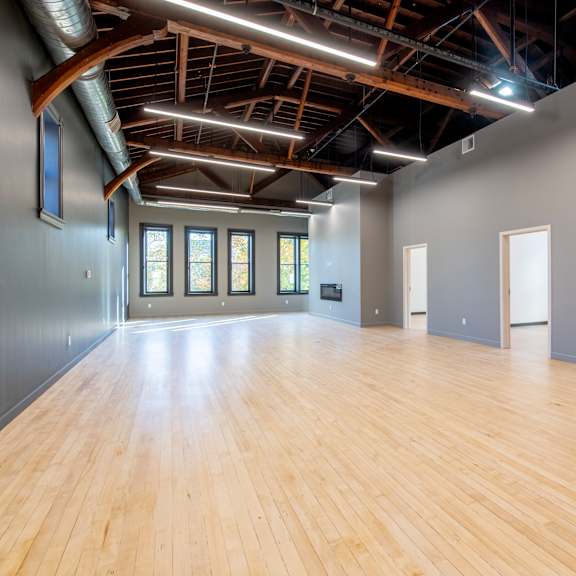 a spacious room with wooden floors and a high ceiling with exposed beams.