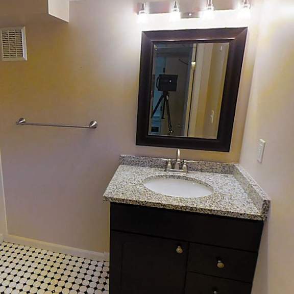 a bathroom with a sink, mirror, and shower.