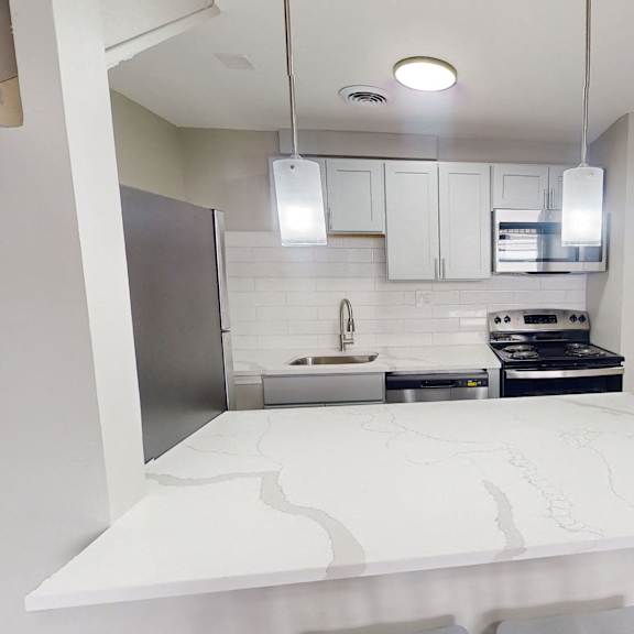 a modern kitchen with a white countertop and stainless steel appliances.