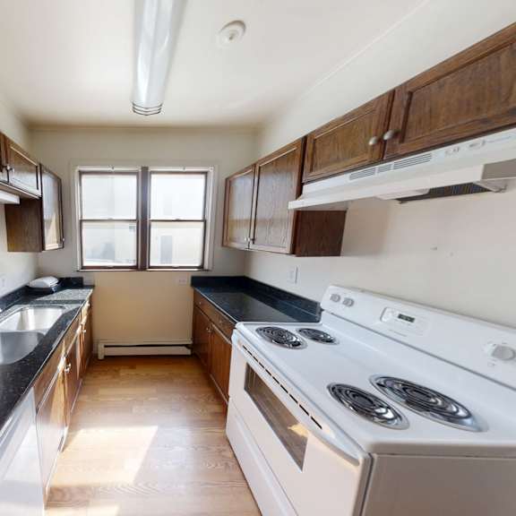 a kitchen with a stove, sink, and cabinets.