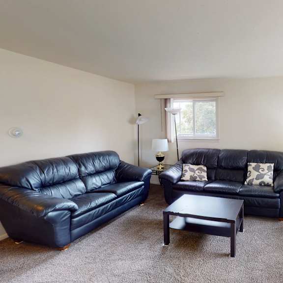 a living room with two black leather couches and a coffee table.
