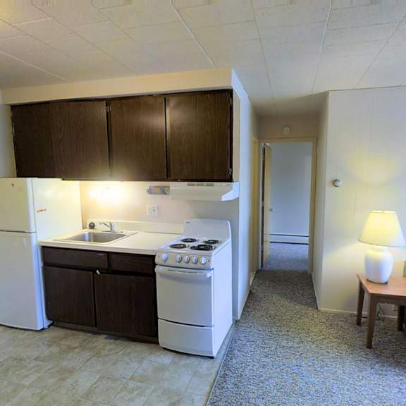 a small kitchen with a refrigerator, oven, and sink.