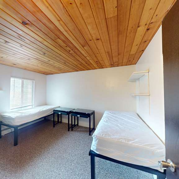 a room with a bed, a table and a dresser.