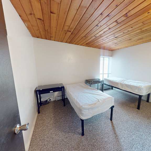 a room with a bed, a bench, and a small table.