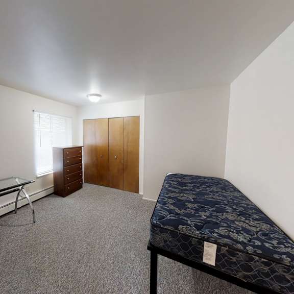 a room with a bed, a bench, and a wardrobe.