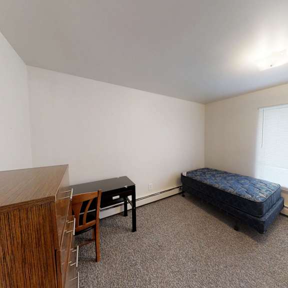 a room with a bed, desk, and chair.