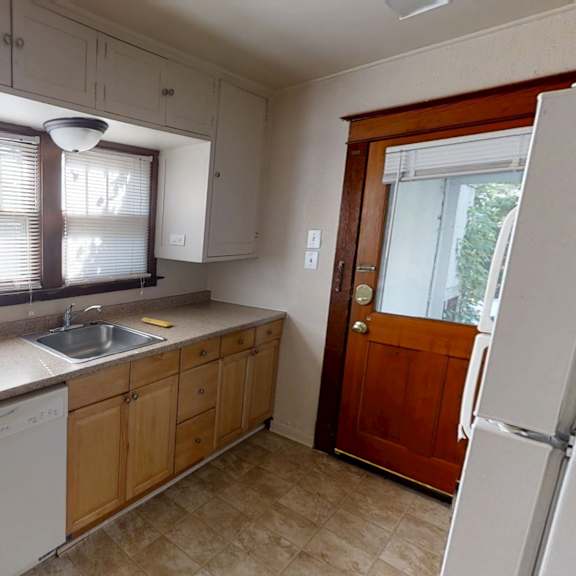 a kitchen with a white dishwasher and wooden cabinets.