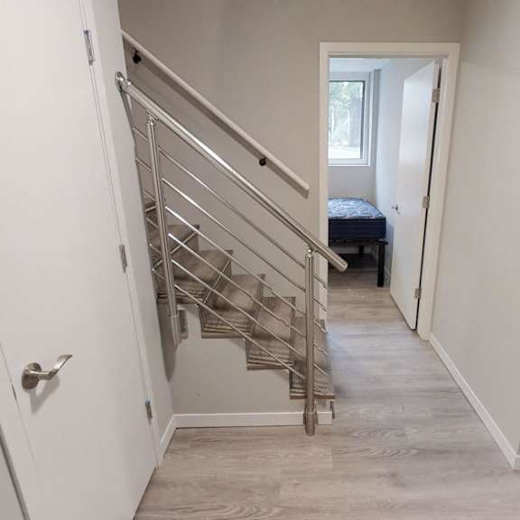 a staircase with a metal railing leads to a bedroom with a bed and a window.