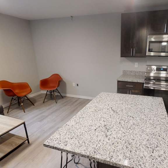 a kitchen with a granite countertop and a dining table with chairs.