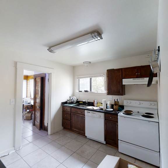 a kitchen with white appliances and a black counter.