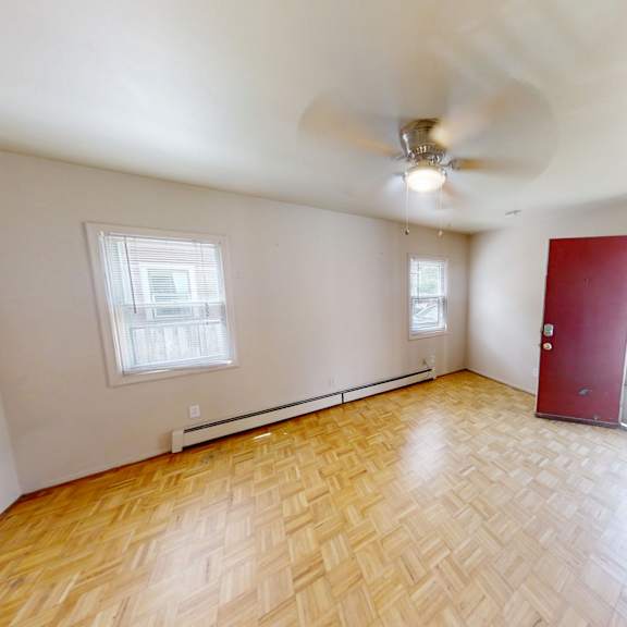 a room with a ceiling fan and wooden flooring.