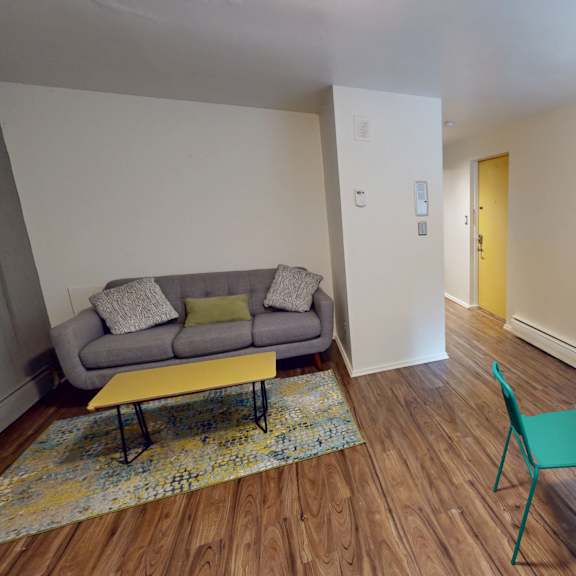a living room with a grey couch, yellow coffee table, and a green chair.