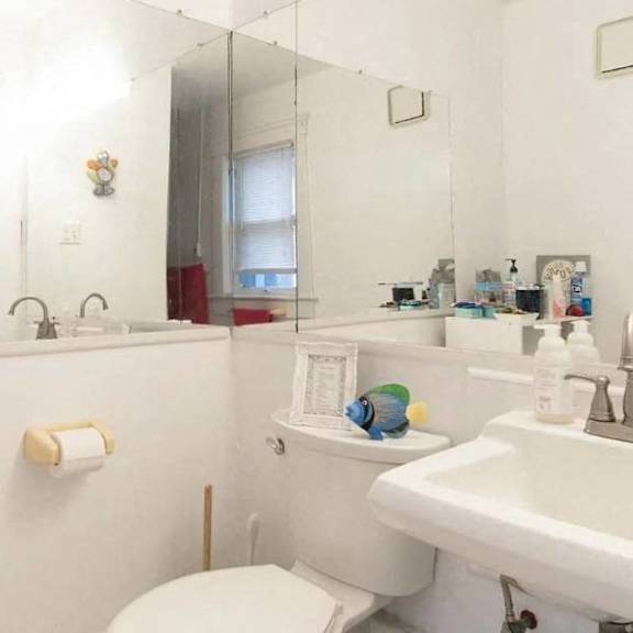 a white bathroom with a toilet, sink, and mirror.