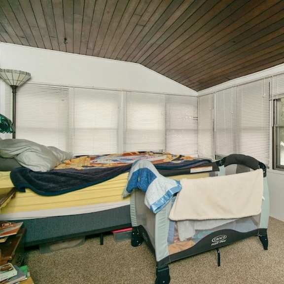 a bedroom with a bed and a window with blinds.