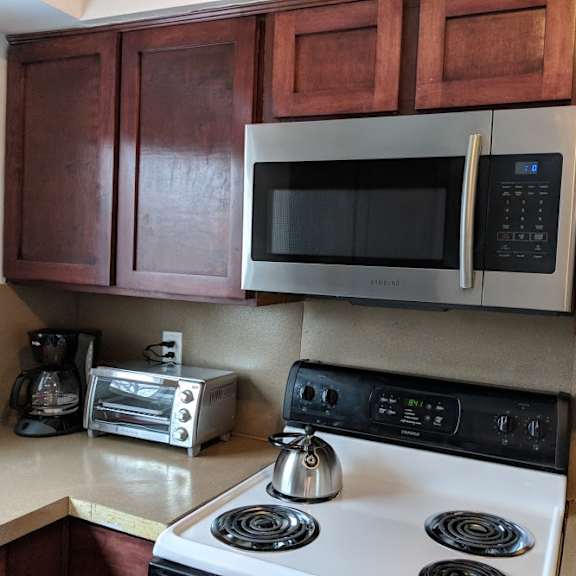 a kitchen with a white stove top oven and a silver microwave above it.