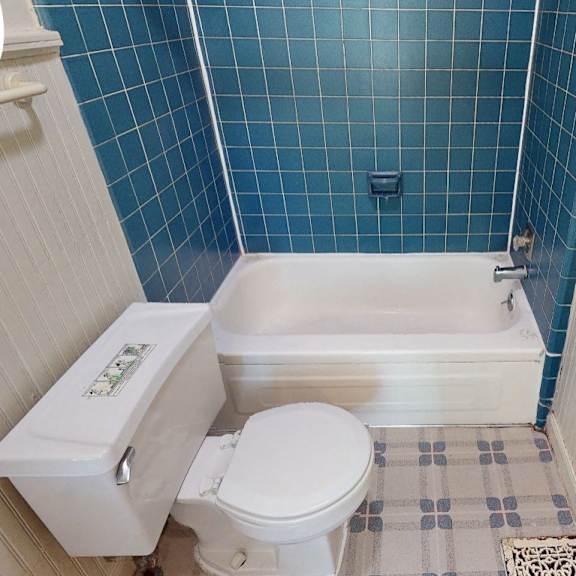 a white toilet with a white lid is in a bathroom with blue tiles.