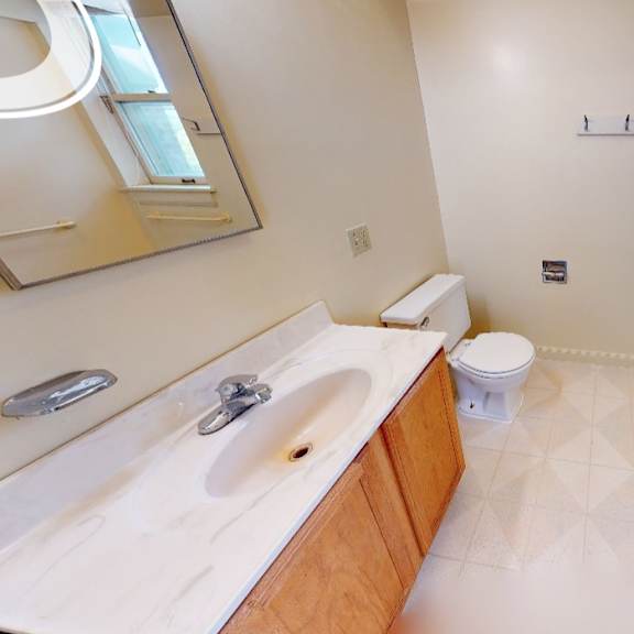 a bathroom with a toilet, sink, and mirror.