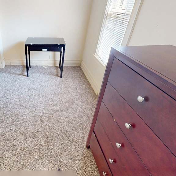 a bedroom with a bed, a small table, and a dresser.