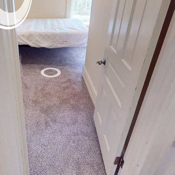 a white door is open to a room with a bed and a carpet.
