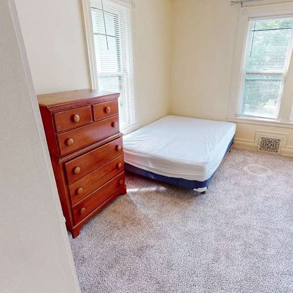 a bedroom with a bed, dresser, and window.