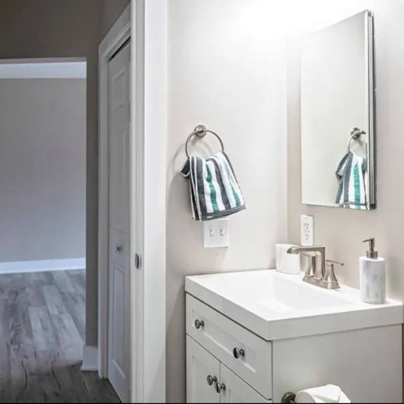 a white bathroom with a toilet, sink, and mirror.