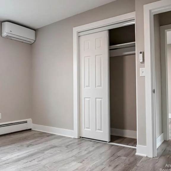 a room with a window, a door, and a wall-mounted air conditioner.