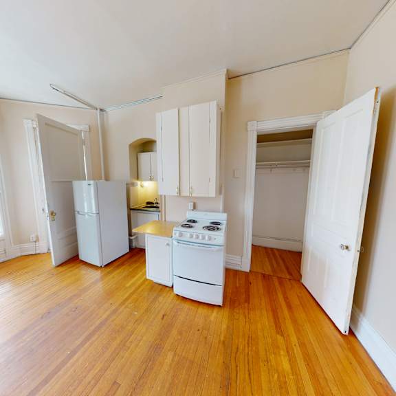 a kitchen with white appliances and wooden floors.