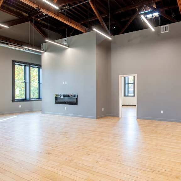 a large empty room with wooden floors and a flat screen tv mounted on the wall.