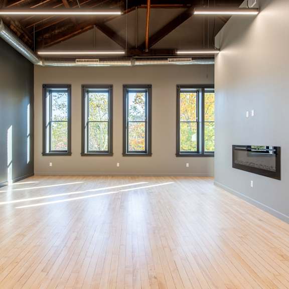 a spacious room with wooden floors and large windows.