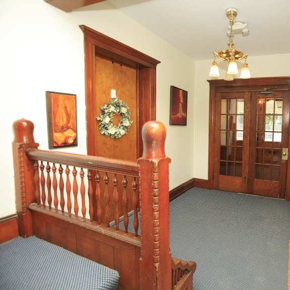 a room with a wooden banister and a wreath on the wall.