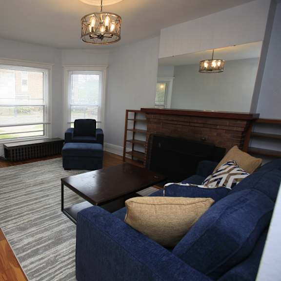 a living room with a blue couch and a wooden chair.