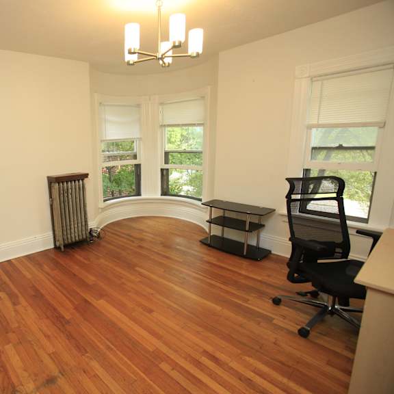 a room with wood floors and a black office chair.