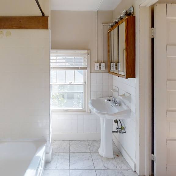 a white bathroom with a sink and mirror.