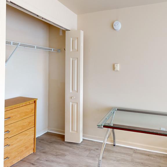 a glass table with metal legs sits in a room with a white wall and a door.