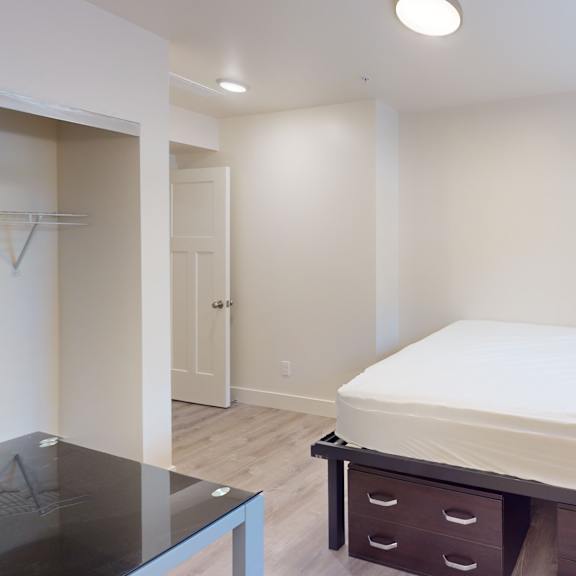 a bedroom with a bed, nightstand, and a glass table.