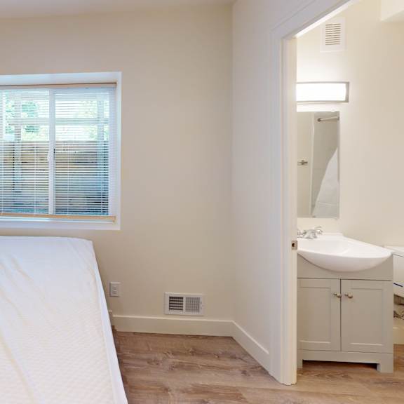 a white bedroom with a bed, sink, and window.