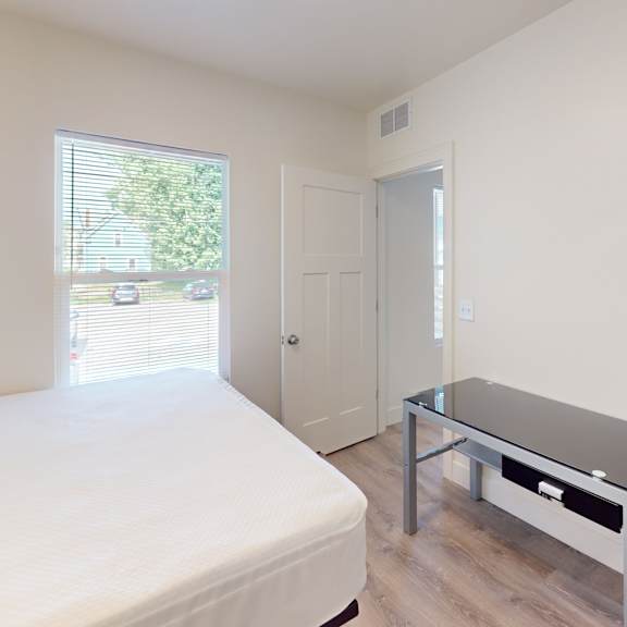 a bedroom with a bed, a table, and a window.