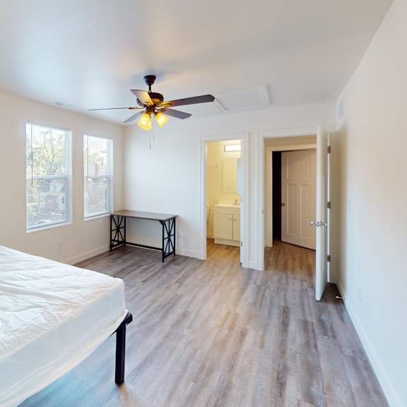 a bedroom with a bed, a ceiling fan, and a wooden floor.