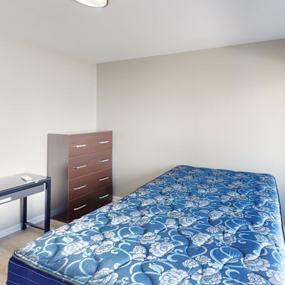 a bedroom with a blue bedspread and a window overlooking a parking lot.