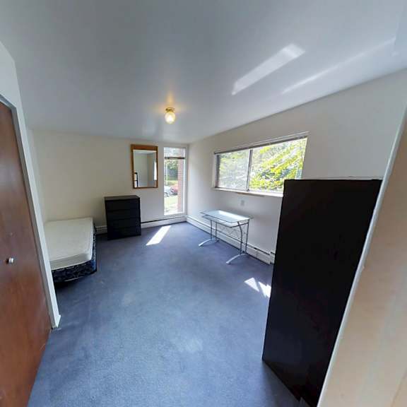 a room with a brown door, a black chair, and a white sofa.