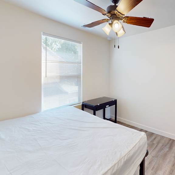 a bedroom with a bed, a ceiling fan, and a window.