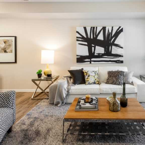 a living room with a white couch, a wooden coffee table, and a large abstract painting on the wall.