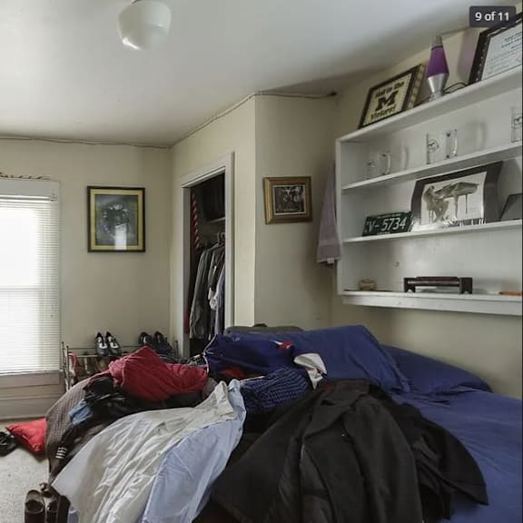 a bedroom with a bed, dresser, and a window with blinds.