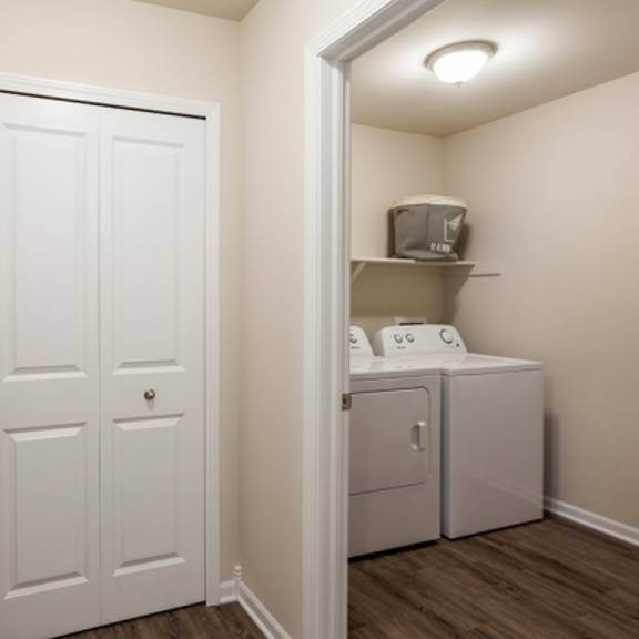 a white door is in a hallway with a washer and dryer in the other room.