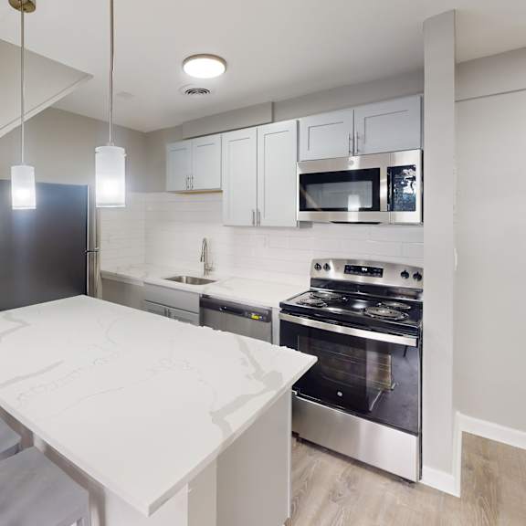 a modern kitchen with a stainless steel refrigerator, microwave, and oven.