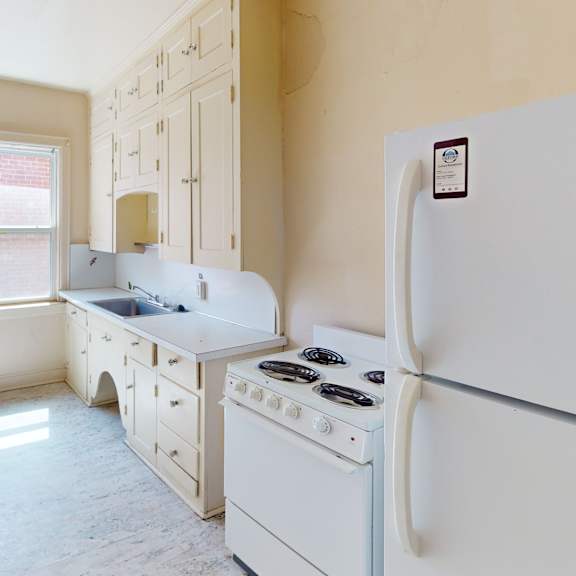 a white kitchen with a fridge, stove, and sink.