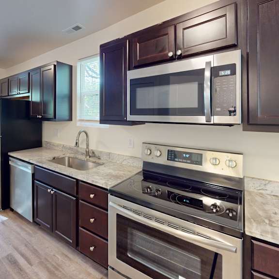 a kitchen with dark brown cabinets and stainless steel appliances.