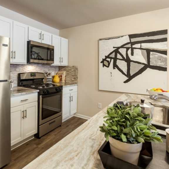 a modern kitchen with a stainless steel refrigerator and white cabinets.
