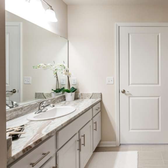 a bathroom with a sink, mirror, and a white door.