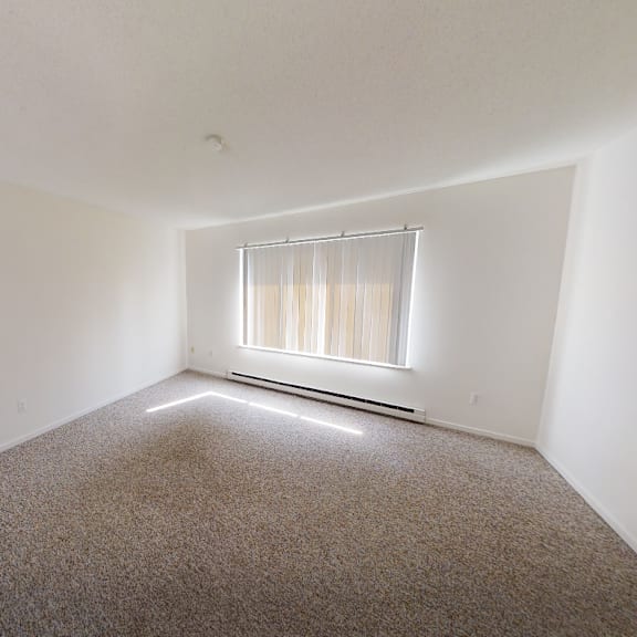 a room with a carpeted floor and a window with blinds.